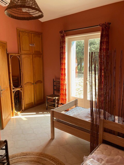 Chambre aux murs terracotta avec lits jumeaux, rideaux colorés et lumière naturelle.