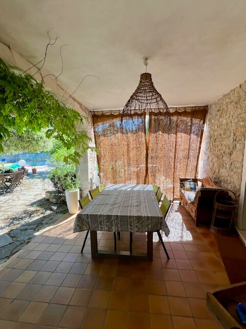 Patio rustique avec table décorées, luminaires tressés etrideaux naturels filtrant la lumière