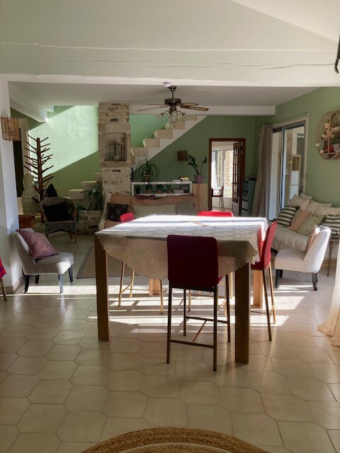 - Salle à manger chaleureuse avec table en bois, chaises rouges et escalier en pierre.
