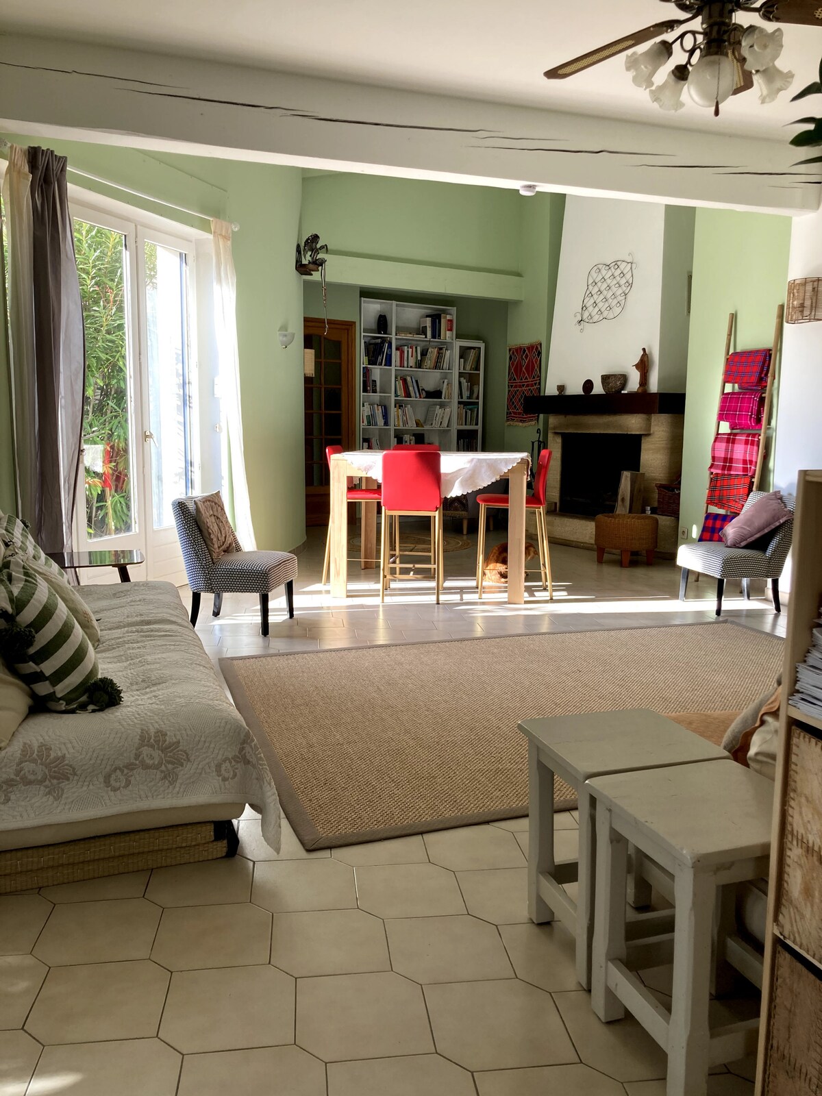 Salon lumineux avec canapé, fauteuils à motifs et bibliothèque intégrée près de la cheminée.
