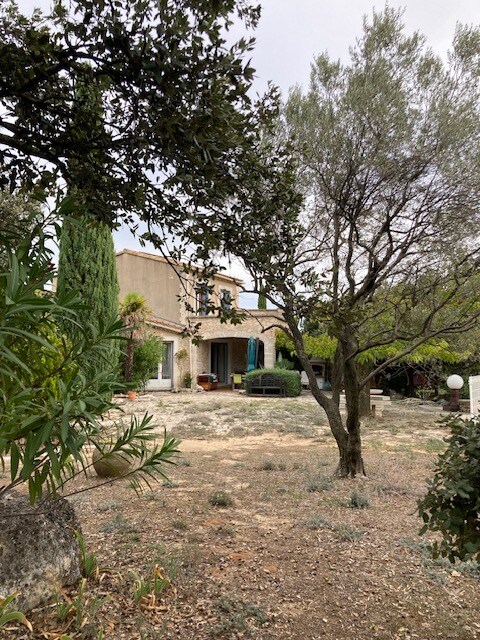 Villa Naturasana avec volets bleus, jardin méditerranéen, mobilier extérieur et plantes en pot.