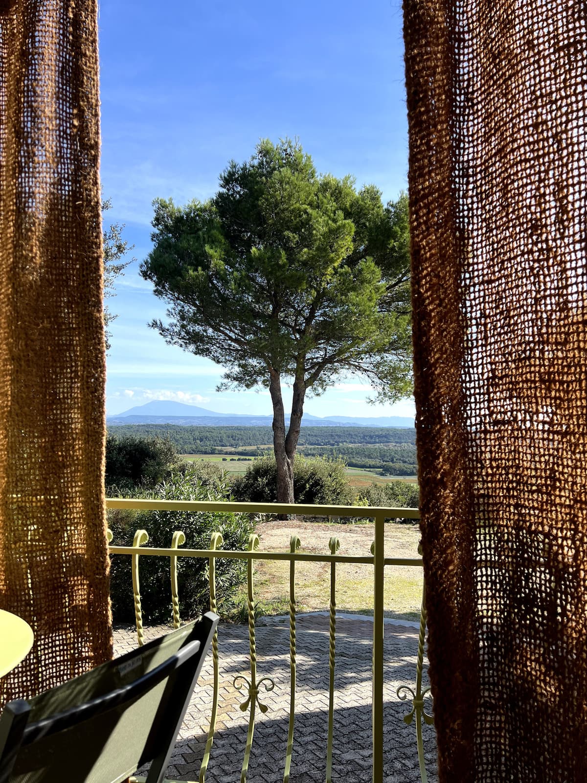 - Vue panoramique sur le mont ventoux, encadrée par rideaux et rambarde jaune, sur champs et montagnes.